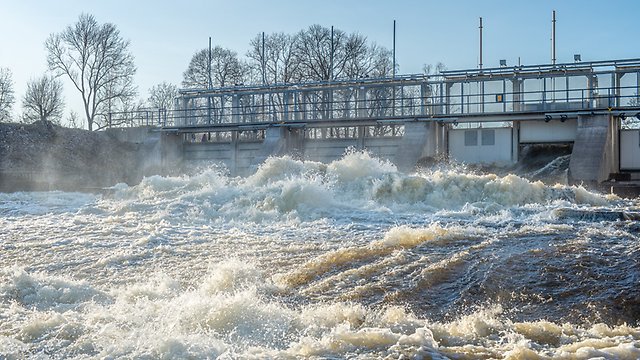 Vatten som forsar ur öppen dammlucka i en vattenkraftsdamm.