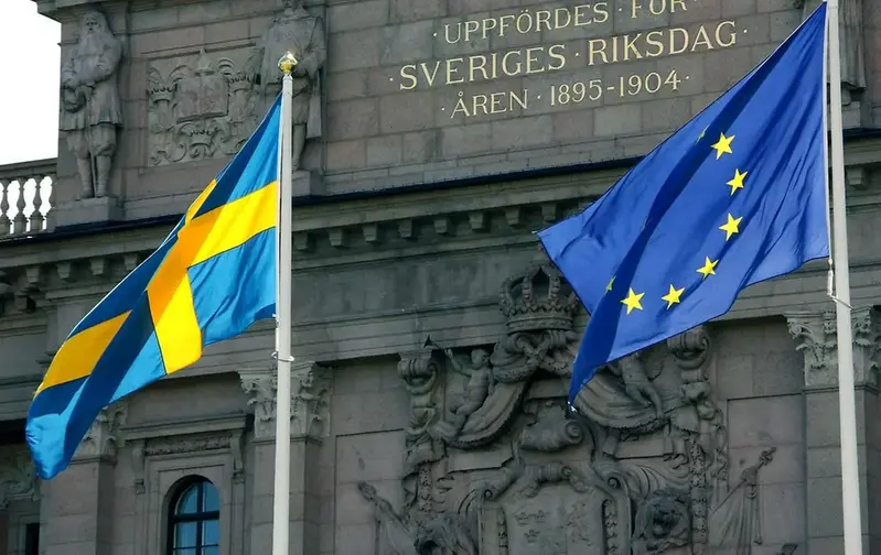Svenska flaggan och EU flaggan framför svenska riksdagshuset