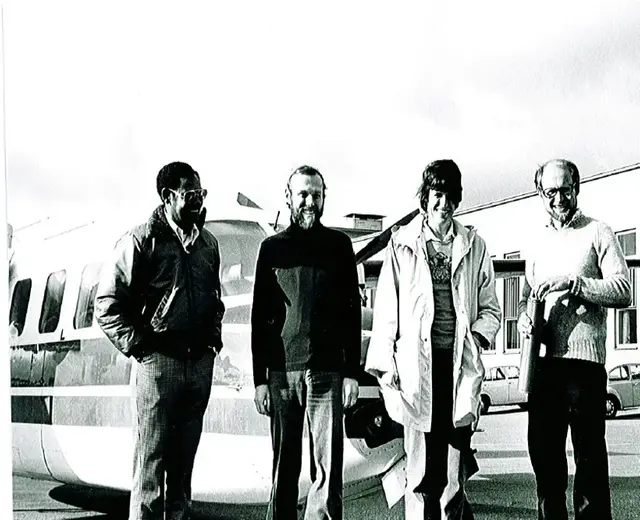 Svartvitrbild från 70-tal. personer framför flygplan.